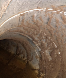 The clear water line and buildup in this ductwork are evidence of water damage.